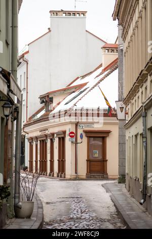 Bella stradina della città vecchia di Vilnius, con vecchi edifici e lampioni in inverno con neve sui ciottoli, verticale Foto Stock