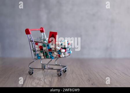 Un carrello traboccante di pillole colorate con una freccia rossa rivolta verso l'alto. Copia spazio. L'aumento del costo dei farmaci da prescrizione. Foto Stock