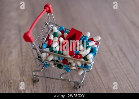 Un carrello traboccante di pillole colorate con una freccia rossa rivolta verso l'alto. Copia spazio. L'aumento del costo dei farmaci da prescrizione. Foto Stock