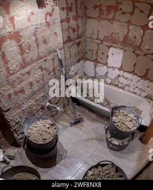 Bagno prima della ristrutturazione in fase di demolizione con vasca piena di detriti. Lavori di ristrutturazione della casa Foto Stock