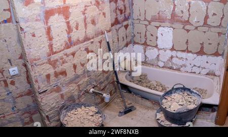 Bagno prima della ristrutturazione in fase di demolizione con vasca piena di detriti. Lavori di ristrutturazione della casa Foto Stock