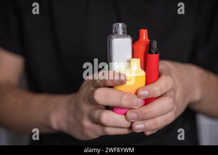 Regno Unito per vietare vapes usa e getta (e-sigarette) per proteggere la salute dei bambini. Ragazzo adolescente con vapori monouso e vapori monouso fumanti Foto Stock