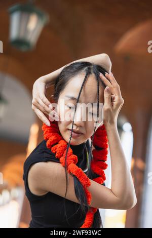 Una giovane ballerina con una vivace sciarpa rossa chiude gli occhi in un momento di concentrazione prima di una sessione di danza urbana. Foto Stock