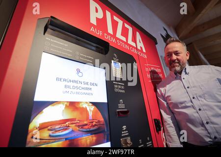PRODUZIONE - 07 dicembre 2023, Schleswig-Holstein, Grömitz: Patrick Enste, Project Manager presso gli hotel Lieblingsplatz, si trova in una macchina per la pizza in un chiosco di distributori automatici sul lungomare. Foto: Christian Charisius/dpa Foto Stock