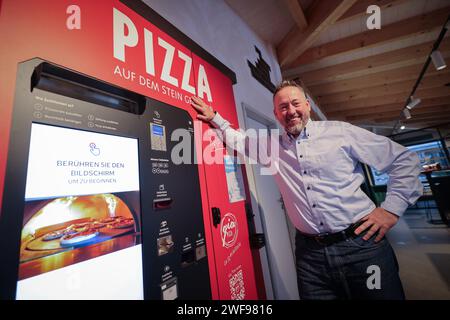 PRODUZIONE - 07 dicembre 2023, Schleswig-Holstein, Grömitz: Patrick Enste, Project Manager presso gli hotel Lieblingsplatz, si trova in una macchina per la pizza in un chiosco di distributori automatici sul lungomare. Foto: Christian Charisius/dpa Foto Stock