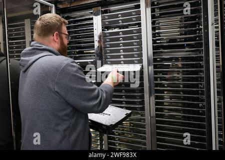 PRODUZIONE - 07 dicembre 2023, Schleswig-Holstein, Grömitz: Un dipendente sente i vani frigoriferi di un distributore automatico di pizza in un chiosco di distributori automatici sul lungomare. Foto: Christian Charisius/dpa Foto Stock