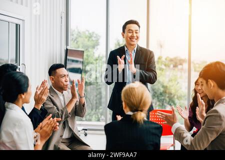 Durante un seminario, un insegnante spiega le strategie e il pubblico diversificato alza le mani per chiedere Foto Stock