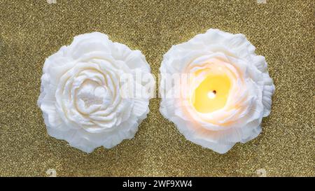 Candela di cera di soia fatta a mano a forma di fiore su sfondo dorato. Vista dall'alto di due candele. Foto Stock