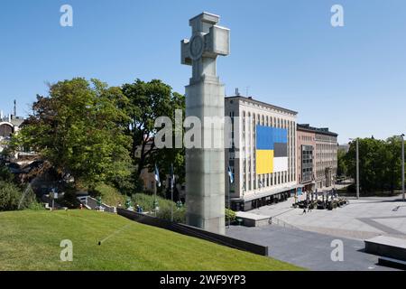 Enorme bandiera blu gialla dell'Ucraina sulla facciata di un edificio sulla Piazza della libertà con la Croce della libertà a sinistra nella città vecchia di Tallinn, Estonia Foto Stock