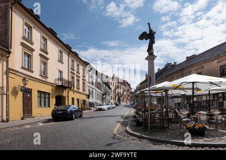 Paesaggio urbano di Vilnius in via Užupio con case colorate e turisti su una terrazza coperta, vicino alla statua "Angelo di Užupis" Foto Stock