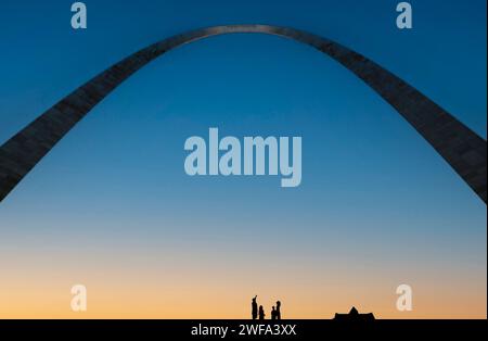 Un gruppo di persone si staglia contro il cielo crepuscolo sotto l'iconico Gateway Arch di St Louis, Missouri. Foto Stock