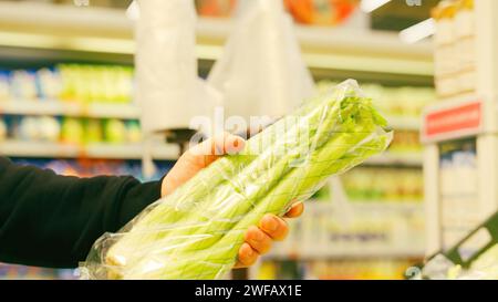 Un giovane che compra verdure al supermercato. Comprate un mucchio di sedano al supermercato. Foto Stock