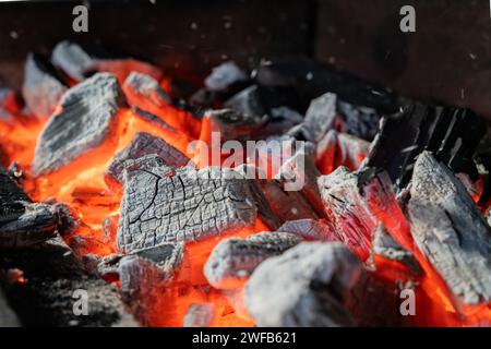 Foto di carboni vivi che scintillano caldi che bruciano in uno sfondo barbecue. Un primo piano di carboni da barbecue in fiamme. Foto Stock