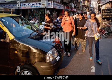 Donne indiane che si rivolgono a un tassista mentre cercano di attraversare la trafficata Kalbadevi Road a Bhuleshwar, Mumbai, India, un'area commerciale molto congestionata Foto Stock