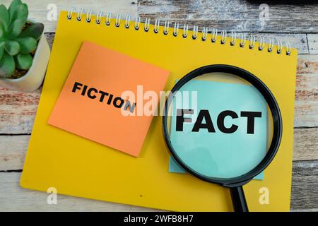 Concept of Fiction o Fact scrivere su appunti isolati su un tavolo di legno. Foto Stock