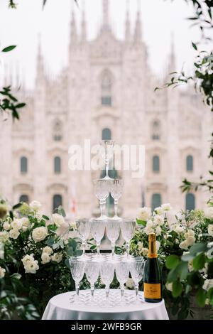 Pila di bicchieri su un tavolo accanto a una bottiglia di champagne su un balcone che si affaccia sul Duomo. Milano, Italia Foto Stock