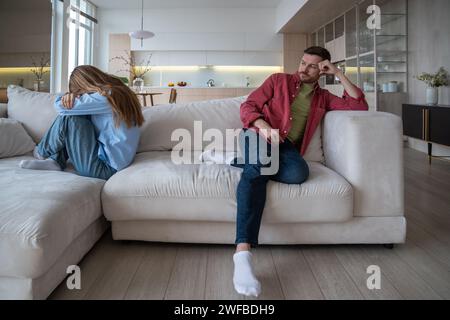 La famiglia, la coppia, la moglie e il marito si siedono separati sul divano a casa senza parlare dopo la lite Foto Stock