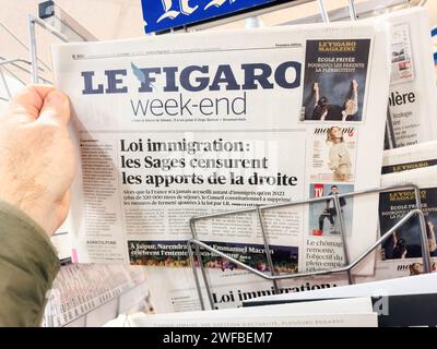 Parigi, Francia - 26 gennaio 2024: POV di una mano maschile che tiene in mano l'ultimo quotidiano le Figaro con la "Loi Immigration" promulgata da Emmanuel Macron e le disparità sociali che crea Foto Stock