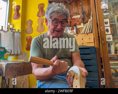 Maestro liutaio liutaio che lavora al rotolo di violino nel suo laboratorio a Cremona Foto Stock