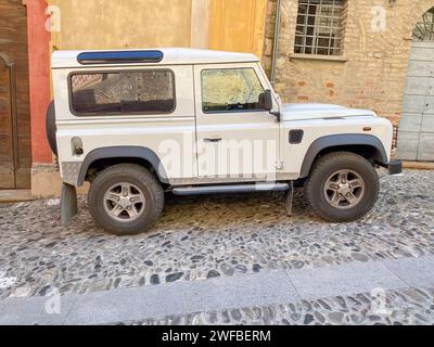 Castell'Arquato, Italia - giugno 25 2023 Land Rover Defender 90, classico osso bianco degli anni '90, corto parcheggiato in salita nel borgo medievale Foto Stock