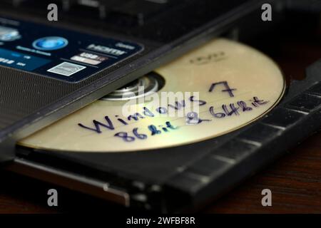 Concetto di installazione illegale del software Windows con Windows 7 a 86 bit e 64 bit crack su CD pronto per essere inserito in un'unità masterizzatore del computer portatile per l'installazione Foto Stock