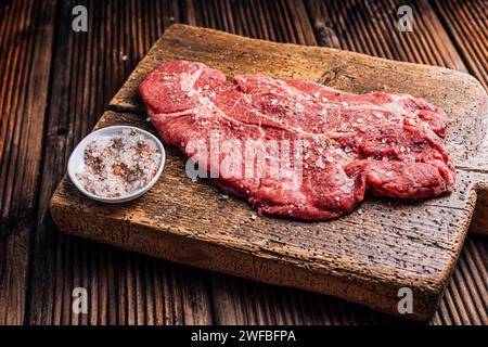 Bistecca di manzo crudo di manzo manzo condita con sale e pepe su tagliere di legno Foto Stock