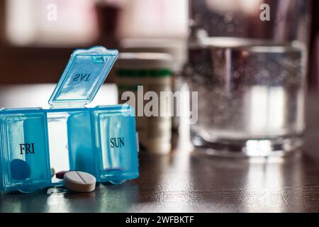 Organizzatore di pillole con una varietà di pillole e supplemento. Organizer settimanale per pillole sul tavolo. Confezione di pillole giornaliere con farmaci e integratori alimentari. Foto Stock