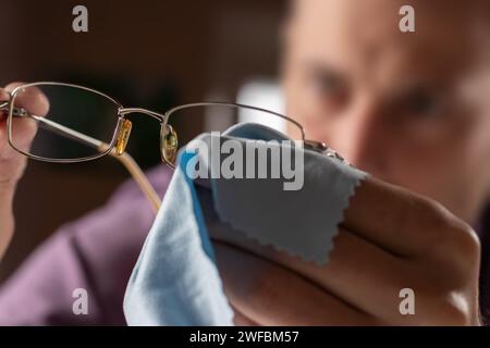 Pulizia degli occhiali. Un uomo gli asciuga gli occhiali con un panno. Messa a fuoco selettiva Foto Stock