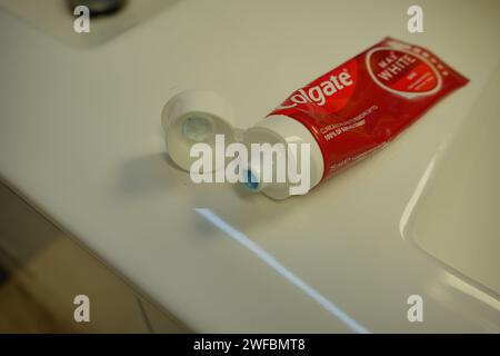 Dentifricio luminoso colgate aperto in rosso e bianco su un bancone del bagno pulito e bianco Foto Stock