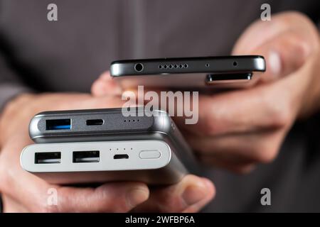 Le mani dell'uomo hanno uno smartphone e un caricabatterie powerbank. STILL Life Modern Digital Concept Foto Stock