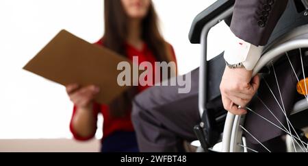 L'uomo in tuta su sedia a rotelle comunica con la donna Foto Stock