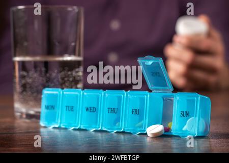 Organizzatore di pillole con una varietà di pillole e supplemento. Organizer settimanale per pillole sul tavolo. Confezione di pillole giornaliere con farmaci e integratori alimentari. Foto Stock