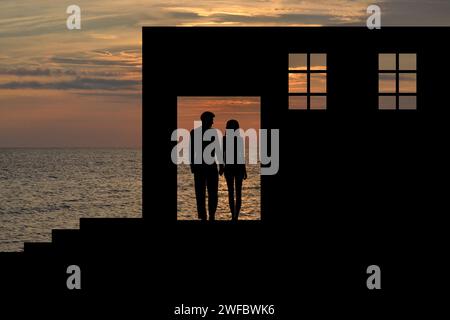 Sagome di amanti sullo sfondo di un edificio abbandonato in riva al mare Foto Stock