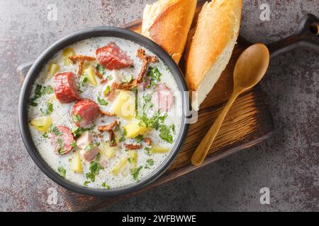 Zalewajka è una deliziosa zuppa di segale acida polacca tradizionale con verdure, salsiccia e funghi secchi da vicino sul piatto sul tavolo. Orizzontale t Foto Stock