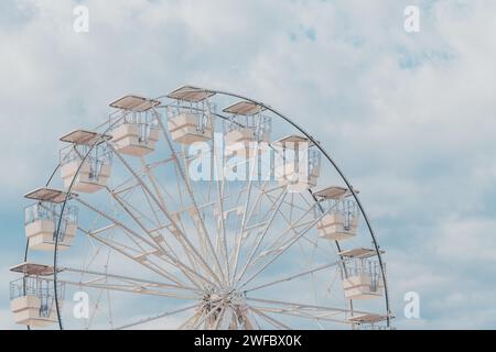 La ruota panoramica per una vista panoramica nel parco divertimenti è una popolare e divertente corsa, girata contro il cielo estivo in una giornata di sole luminoso, concentrazione selettiva Foto Stock