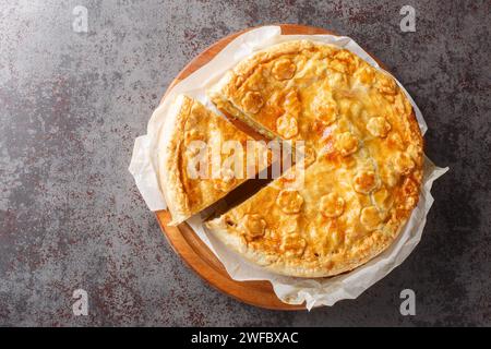 Primo piano della torta di colera con porri svizzeri, patate, mele e formaggio sul tabellone di legno sul tavolo. Vista superiore orizzontale dall'alto Foto Stock