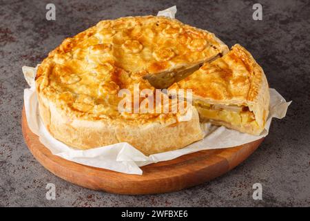 Cucina svizzera Walliser colera cake con patate, porro, mela, primo piano di formaggio sul tabellone di legno sul tavolo. Orizzontale Foto Stock