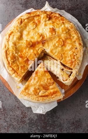 Deliziosa torta svizzera al colera con mela, patate, pera, cipolla e formaggio da vicino su un asse di legno sul tavolo. Vista dall'alto verticale Foto Stock