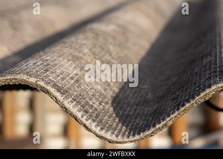 Tetto di una casa di campagna, coperta di ardesia grigia, primo piano. Vecchio tetto coperto di ardesia. Struttura del vecchio tetto, sfondo in ardesia. Foto Stock