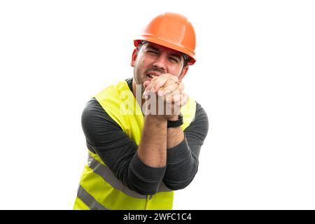 Un costruttore adulto disperato, con una triste espressione, che supplica di chiedere soldi con le mani insieme, indossando abiti da lavoro, giubbotto e elmetto di sicurezza isolato su bianco Foto Stock
