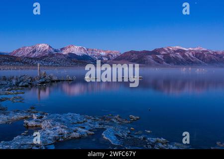 Prima dell'alba nebbia sulle formazioni di tufo sul lago Mono in California. Le montagne della Sierra orientale sono dietro. Foto Stock