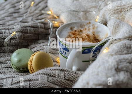 una tazza di caffè e macaron su un piatto lavorato a maglia Foto Stock