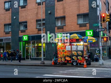 I colori di un carrello alimentare Halal contrastano con il negozio TD Bank a Chelsea a New York giovedì 25 gennaio 2024. (© Richard B. Levine) Foto Stock