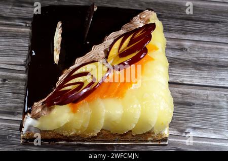 Torta di compleanno composta da due metà diversi pezzi, torta cremosa spugnosa per le celebrazioni, cioccolato fondente, caramello, panna alla vaniglia montata, fette di ananas Foto Stock