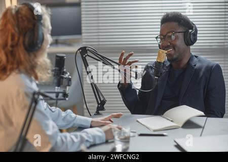 Allegro uomo con le cuffie che parla al Podcast Foto Stock