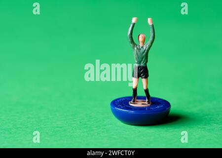Un singolo personaggio di portiere Subbuteo in miniatura dipinto con una camicia verde e pantaloncini neri. Subbuteo è un popolare gioco di calcio da tavolo Foto Stock