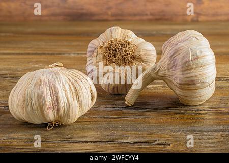 Tre bulbi all'aglio su un tavolo rustico in legno con uno sfondo vintage Foto Stock
