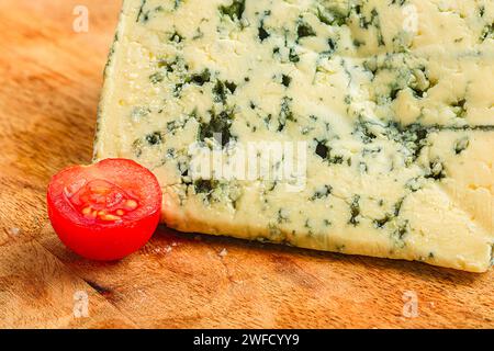 Un formaggio impilato su una tavola rustica di legno con una succosa ciliegia rossa Foto Stock
