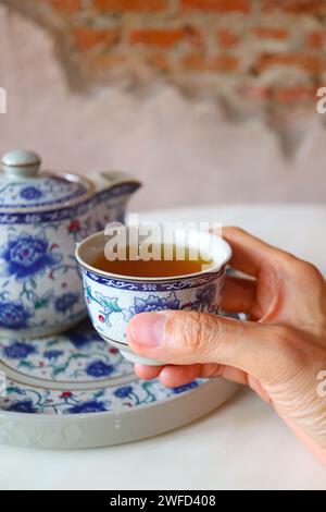 Primo piano della mano con una tazza di tè cinese caldo Foto Stock