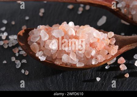 Due cucchiai di legno adagiati su un'ardesia sono riempiti di sale rosa Foto Stock